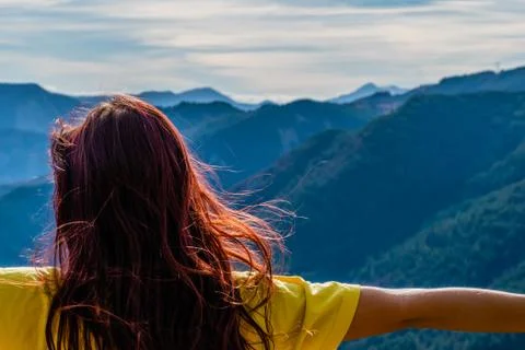 A close-up back view of a young redhead woman in front of the mountain landsc Stock Photos