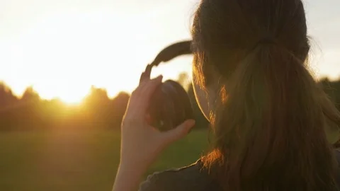 Close-up back of young female putting on headphones in the field. Stock Footage 77067978