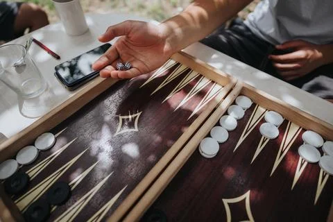 Close up of a backgammon game with dice and players hand outdoors Stock Photos