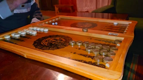 A close-up of a backgammon game in progress shows players moving black and white Stock Footage 301092124