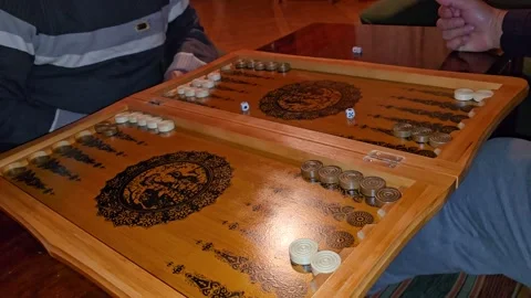 A close-up of a backgammon game in progress shows players moving black and white Stock Footage 301095516