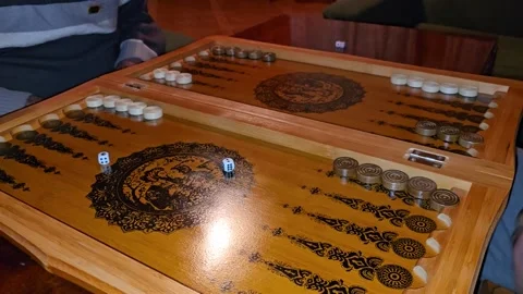 A close-up of a backgammon game in progress shows players moving black and white Stock Footage 301108000