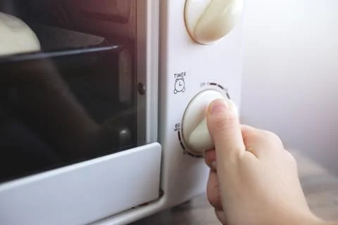 Close up background of hand turning setting timer on microwave oven Stock Photos