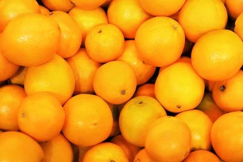 Close-up background image of a large pile of freshly harvested ripe oranges.. Stock Photos