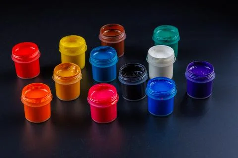 Close-up background of opened small gouache paint jars on black surface 库存照片