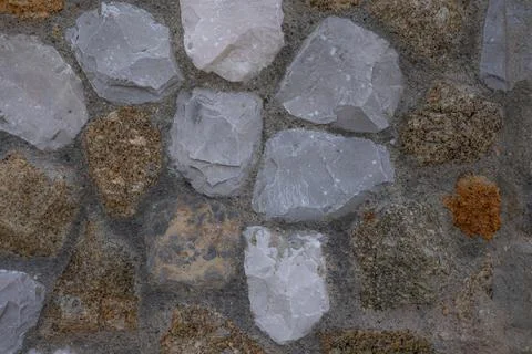 A close-up background of a stone wall with an uneven texture of stones of var Stock Photos