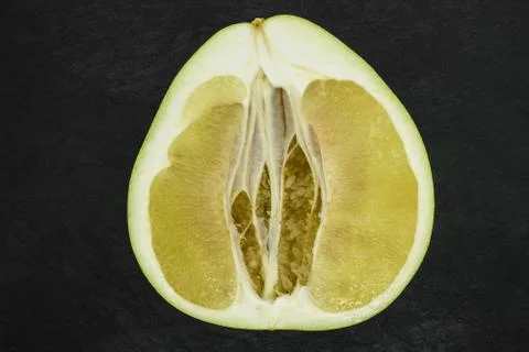 Close-up background surface view of cut pomelo fruit on black stone backgroun Stock Photos