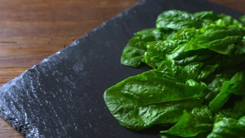 Close-up backlight of freshly picked green spinach leaves placed on a slate plat Vídeos de archivo 126049728