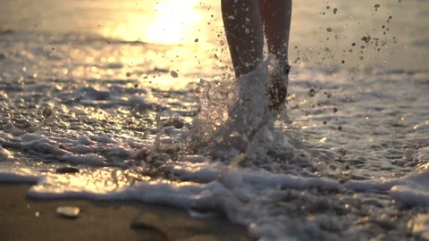Close backside view legs walk in water reflecting sunlight Video stock 102664599