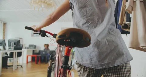 Close up backside view of young caucasian businesswoman carrying bike in modern Stock Footage 112533445