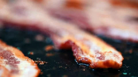 Close-up of bacon slices in frying pan. Bacon sizzling in frying pan, close up. 스톡 동영상 334642333