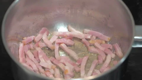 Close up of bacon strips being fried with oil in a saucepan Video stock 252489564