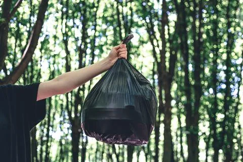 Close-up, a bag of garbage on a blurred background of the forest. Stock Photos