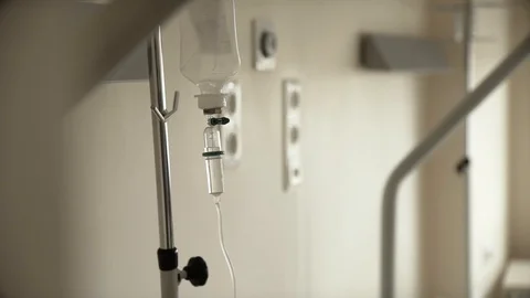 CLOSE UP to a bag of serum dripping and hanging from a special hook inside Stock Footage 100640145