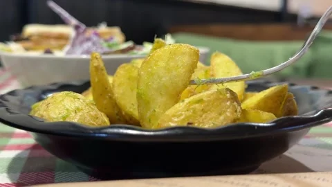Close-up baked potato until crisp, fork with potato wedges Video stock 347255085