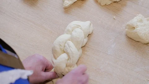 Close-up of baker braiding dough to make braided loaves of bread Stock Footage 108097031