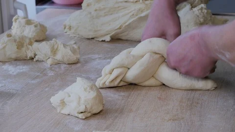 Close-up of baker braiding dough to make braided loaves of bread Stock Footage 108633236