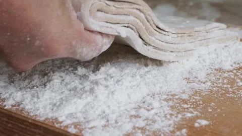 Close-up of Baker Hand Pressing Freshly Folded Puff Pastry Dough on Floured Wood Stock Footage 333522990