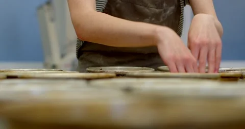Close-up baker hands arranging dough in metal baking tins on bakery counter Stock Footage 344588826