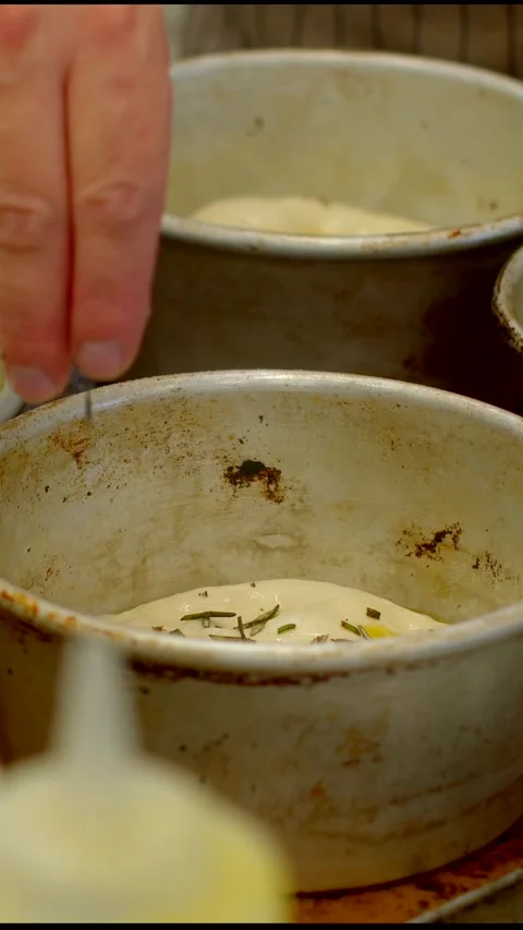 Close-up baker hands arranging egg-washed dough in worn metal tins for, with 库存影片 344576118