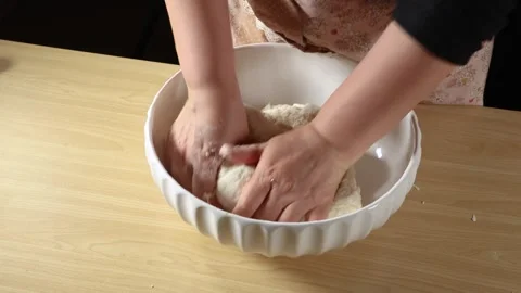 Close Up of Baker Hands Kneading Raw Dough in Bowl on Wooden Table Stock Footage 339560597