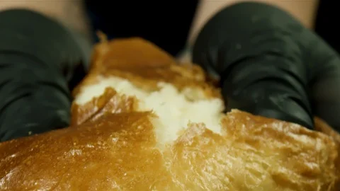 Close up of baker man hands tear hot bread isolated on black background. Stock Stock Footage 128036273