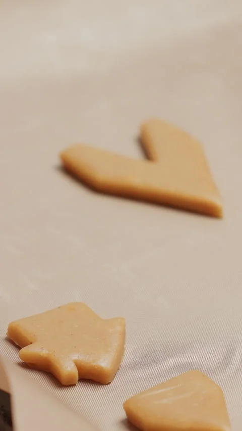 Close-up of baker placing shaped cookie dough on parchment paper for baking in Stock Footage 320340647