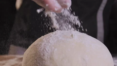 Close-up of baker pours flour on dough. Action. Baker sprinkles pinch of flour Stock Footage 150397197