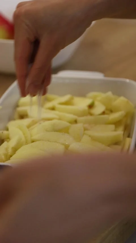 Close-up of a baker sprinkling sugar and lemon juice over sliced apples for a de Stock-Footage 346538259