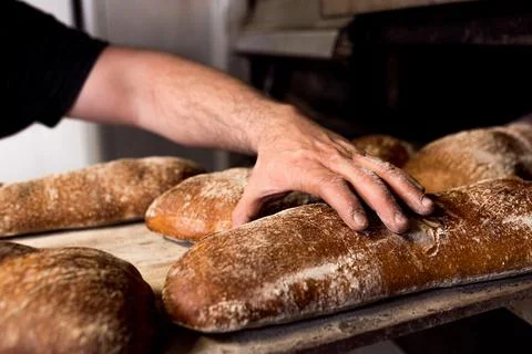 Close up of baker touching and testing fresh hadmade bread with flour in bake Stock Photos