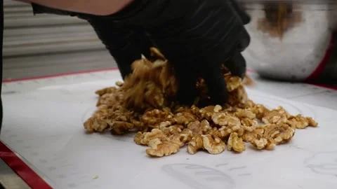 Close-up of baker's hands in black gloves spreading fresh walnuts on a silicone Stock Footage 337751528