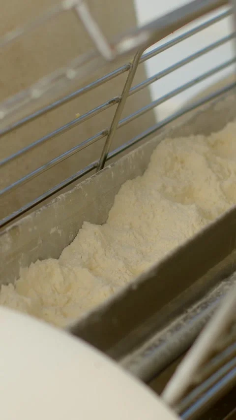 Close-up bakery machine trough filled with pale flour and crumbly dough under 库存影片 344575205