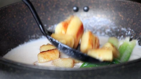 Close up of bananas added to boiling coconut milk in a pan 库存影片 96230487