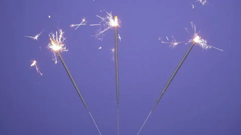 Close up banner of Bright burning three sparklers on a violet or purple Stock Footage 201270529
