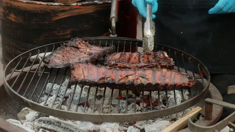 Close up barbecue showing stack of cooked ribs, flames and smoking meats Stock Footage 106061317