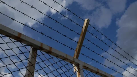 Close-Up Barbed Wire Fence with Rusty Wooden Post and Cloudy Sky Stock Footage 341329386