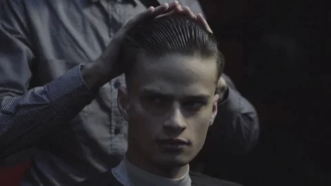 Close-up barber combing the hair of the male client before haircut at a barber Stock Footage