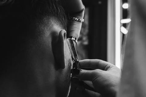 Close-up of barber shaving young client with razor blade Stock Photos