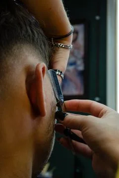 Close-up of barber shaving young client with razor blade Foto stock