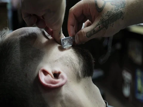 Close up barber's hands with tattoo and client's bearded face. Stock Footage 80463473