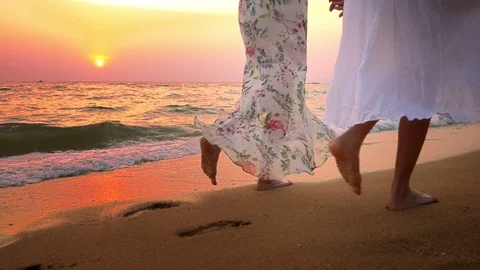 Close up . bare feet on the beach. two young women in white dress walking on the Stock Footage 102058699