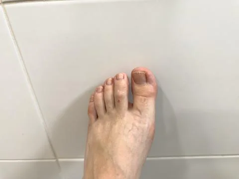 Close-up of bare human foot on tile floor Stock Photos