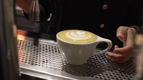 Close-Up of Barista Hands Holding White Latte Cup with Elegant Tulip Art at Stock Footage 336531036