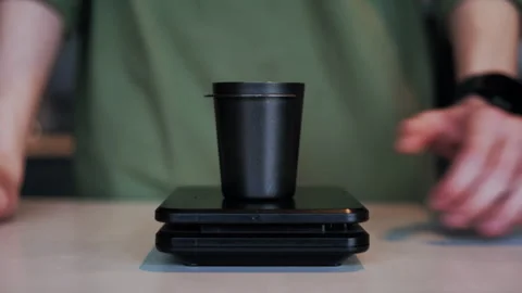 Close-Up of Barista Placing Small Cup on Scales for Coffee Measurement Stock Footage 307587818