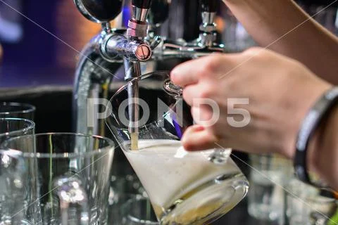 Close-up of barman hand at beer tap pouring a draught lager beer Stock Photos