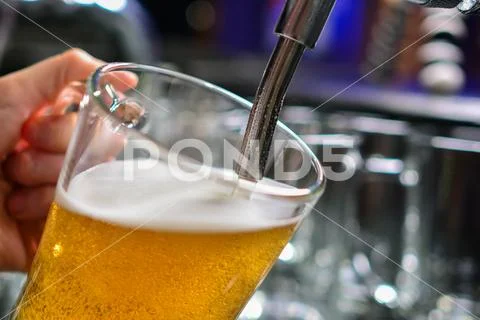Close-up of barman hand at beer tap pouring a draught lager beer Stock Photos