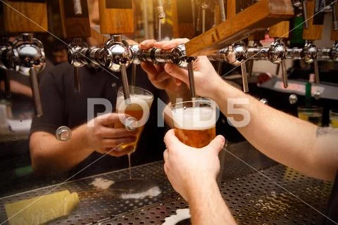Close-up of barman hand at beer tap pouring draught craft beer Stock Photos