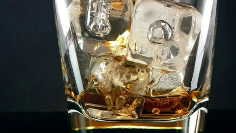 Close-up of  barman pouring whiskey in the drinking glass with ice cubes Видео 76751696
