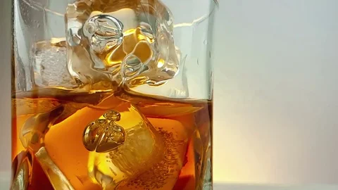 Close-up of  barman pouring whiskey in the drinking glass with ice cubes Video stock 77368561