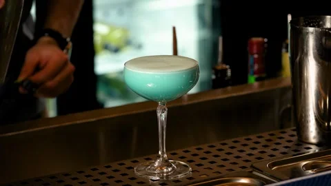Close-up of the barman's hands making a blue cocktail and garnishing it with Stock Footage 264311832